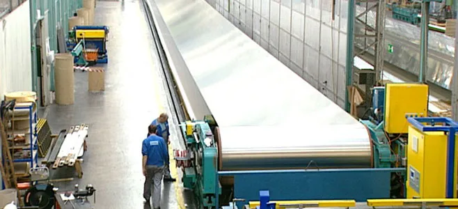 Two men inspecting section of steel conveyor belt system for damages